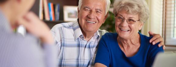 Elderly man and woman smiling at blurry man in foreground
